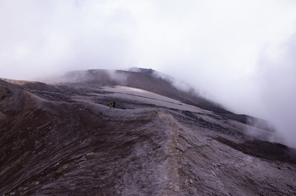 Adventurers hiking through a foggy landscape with rocky mountain slopes.